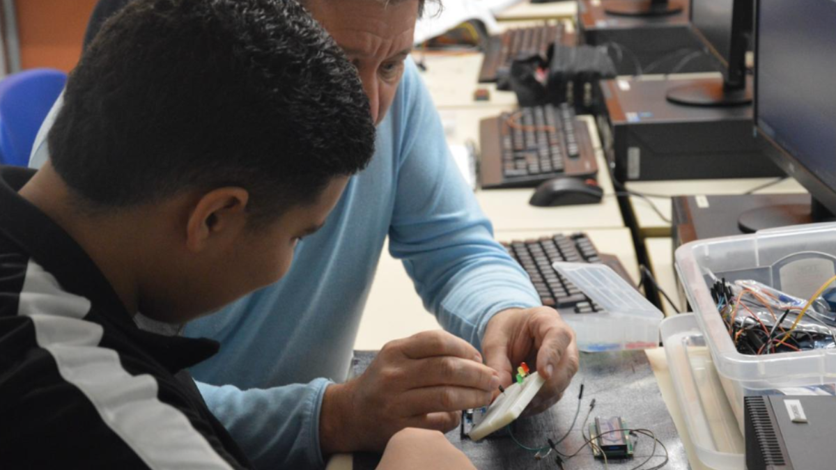 Imagem de um professor dando aula de eletrônica a um aluno